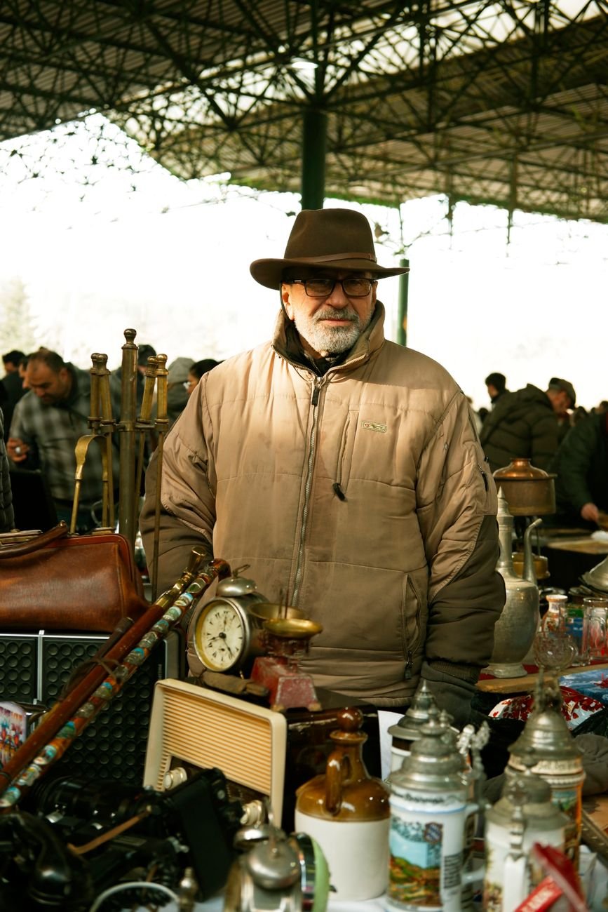 Outdoor flea market scene with a man exploring antique items and collectibles.